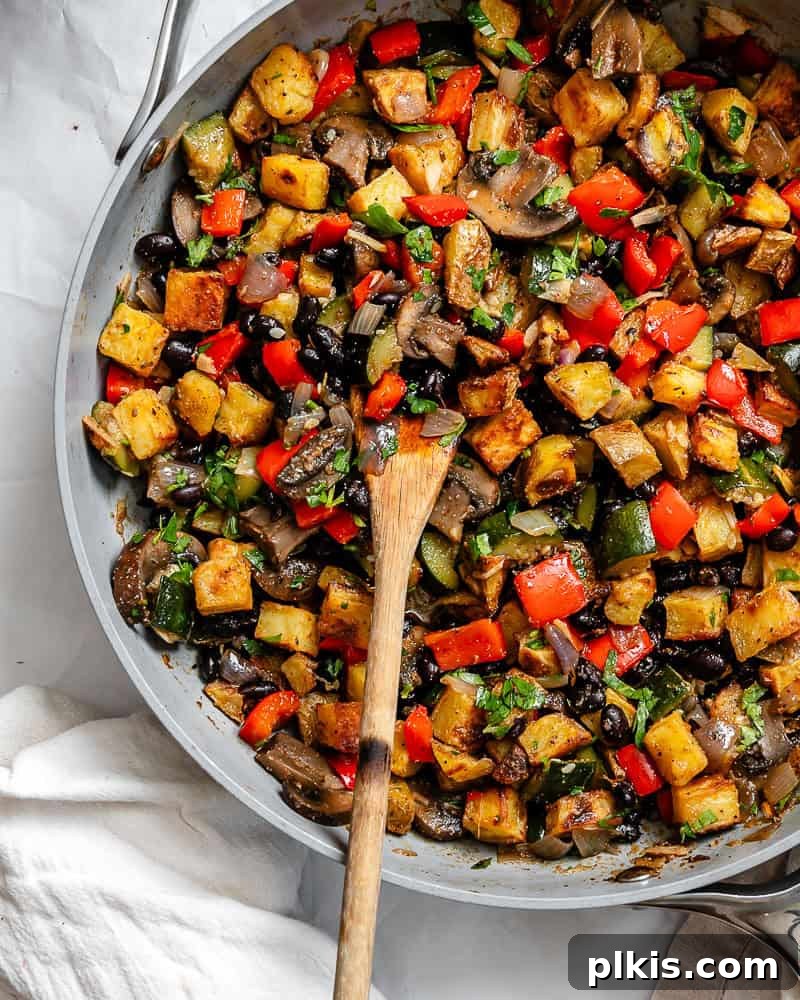 A large cast iron pan filled with the completed Breakfast Potato Hash [Roasted + Skillet], garnished with fresh parsley and ready to be served