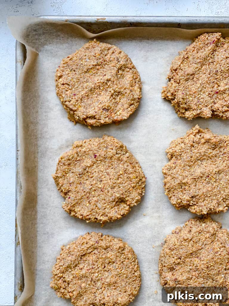 Ultimate Vegan Lentil Burgers 16 Pre-baked lentil patties arranged on a baking tray.