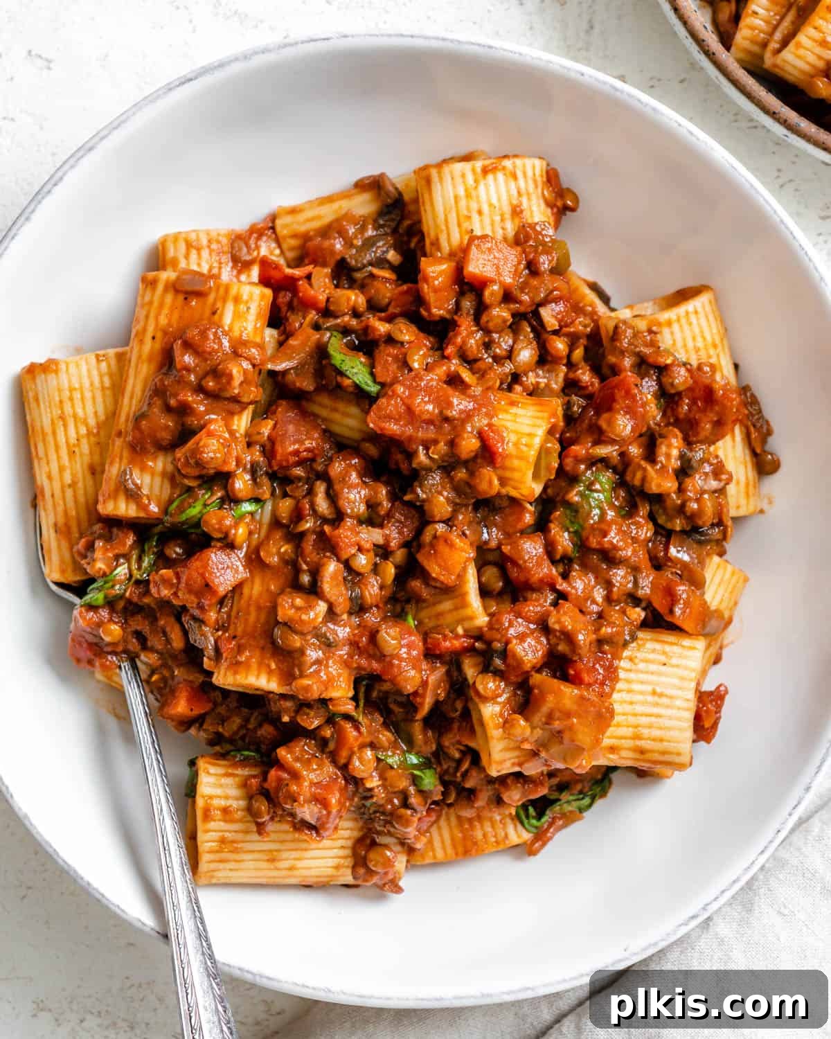 completed Vegan Lentil Bolognese plated on a white plate against a white background