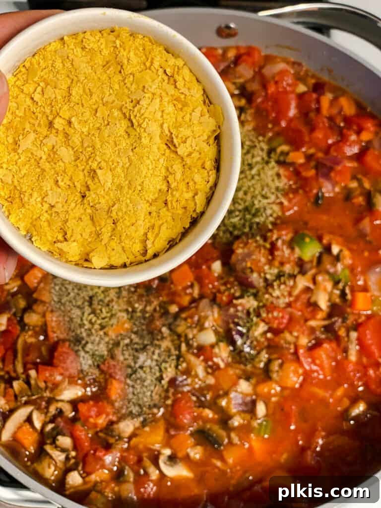 process shot of adding nutritional yeast to pan