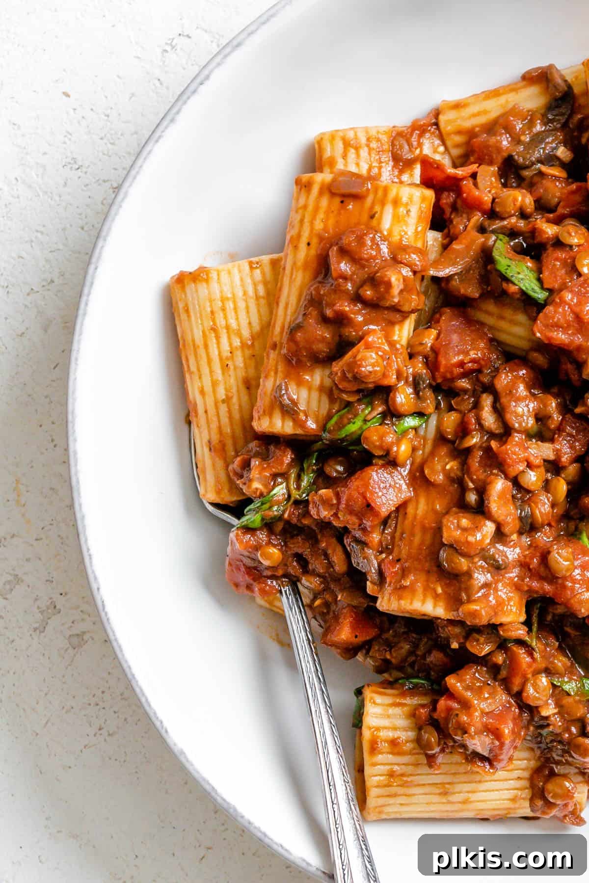 completed Vegan Lentil Bolognese plated on a white plate against a white background