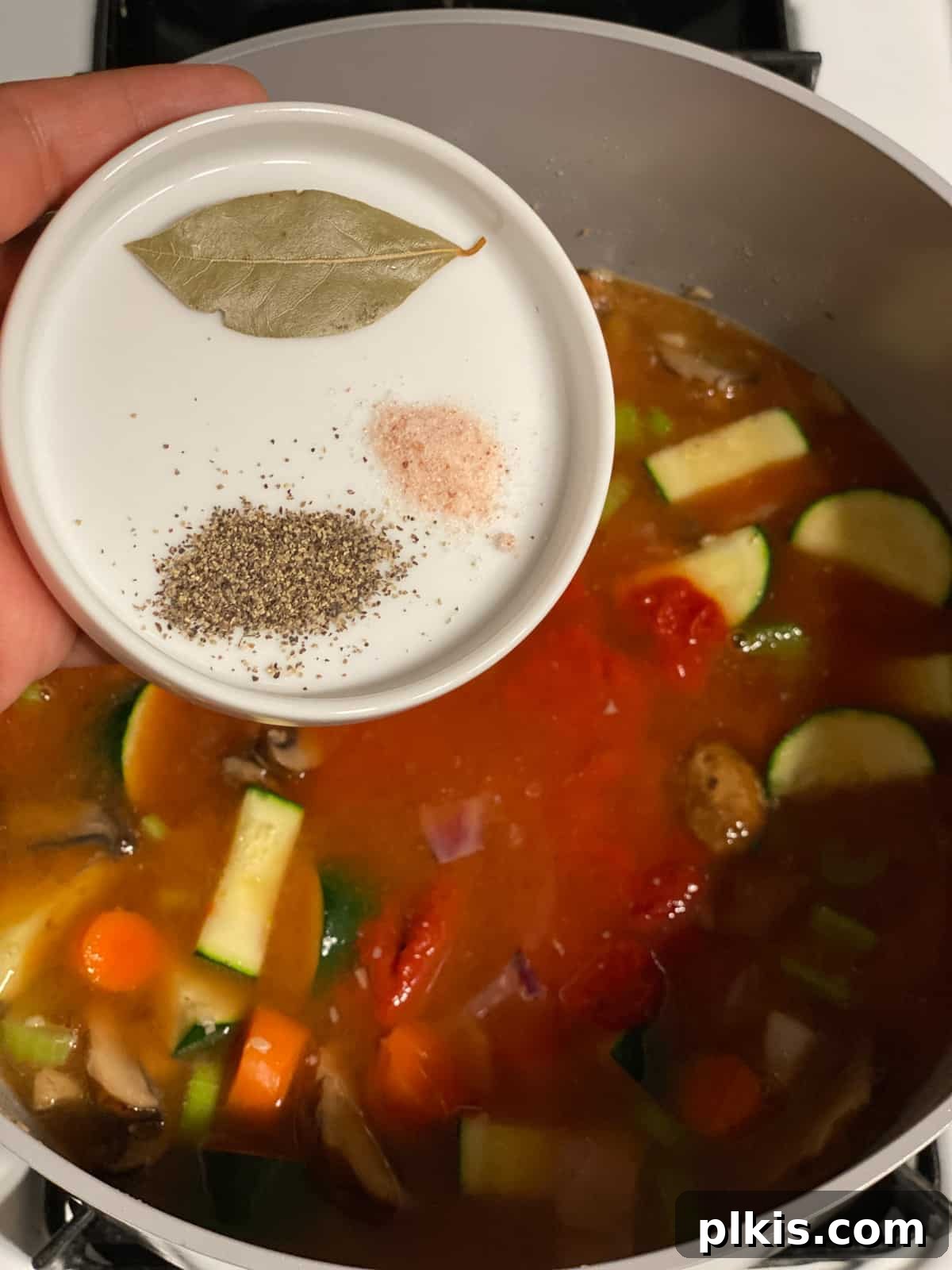 Hearty Tomato Potato Soup 12 Process shot of adding salt and pepper to the soup mixture.