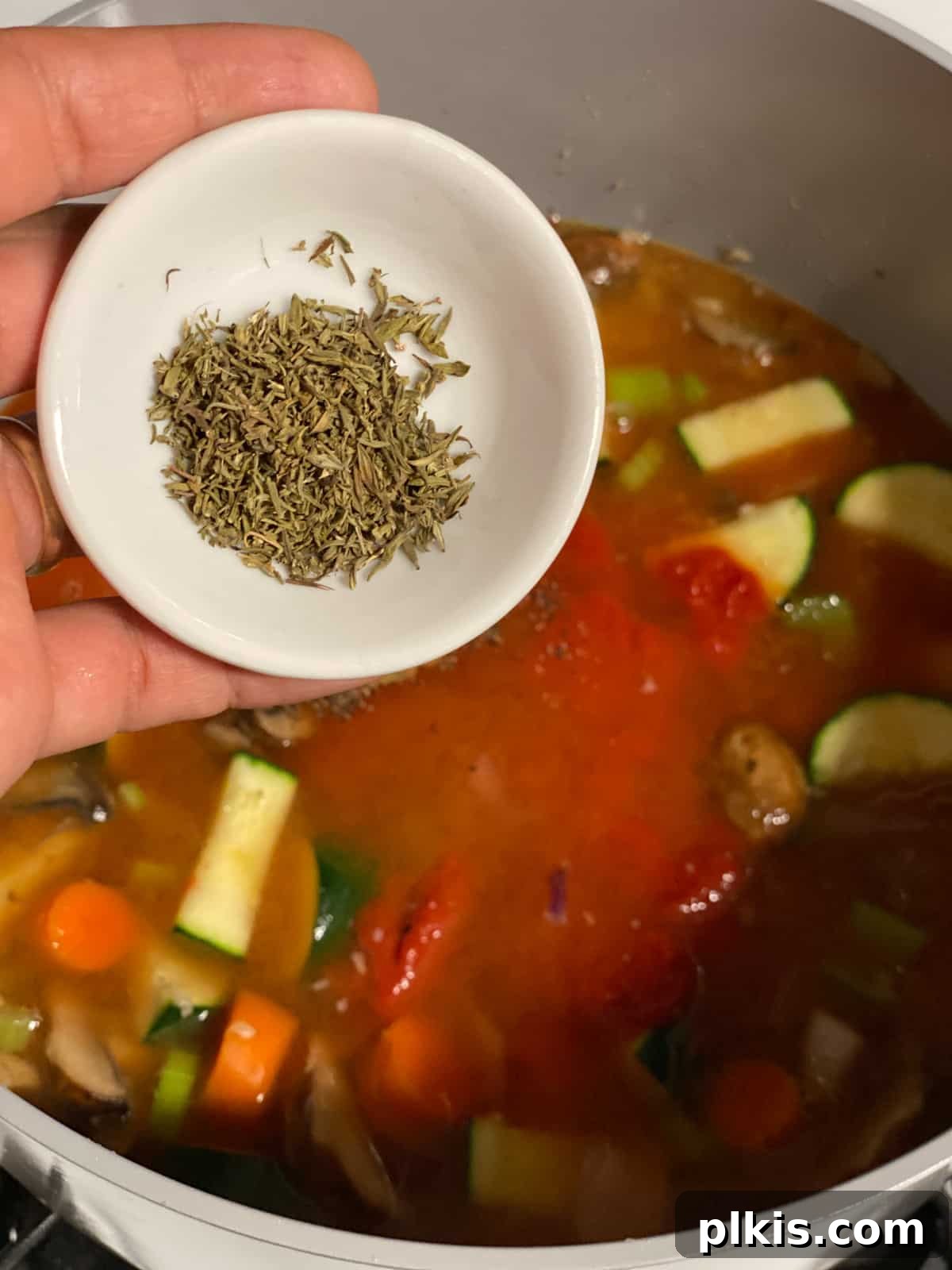 Hearty Tomato Potato Soup 13 Process shot of adding thyme to the soup mixture.