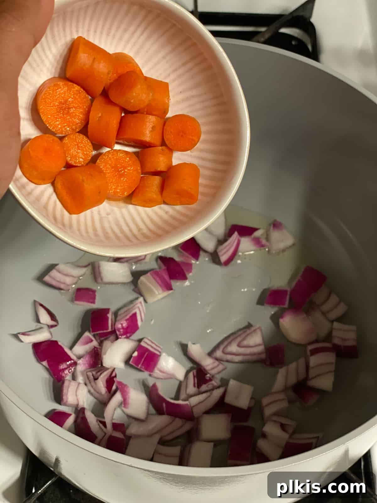 Hearty Tomato Potato Soup 5 Process shot of adding chopped carrots to the pan with other vegetables.