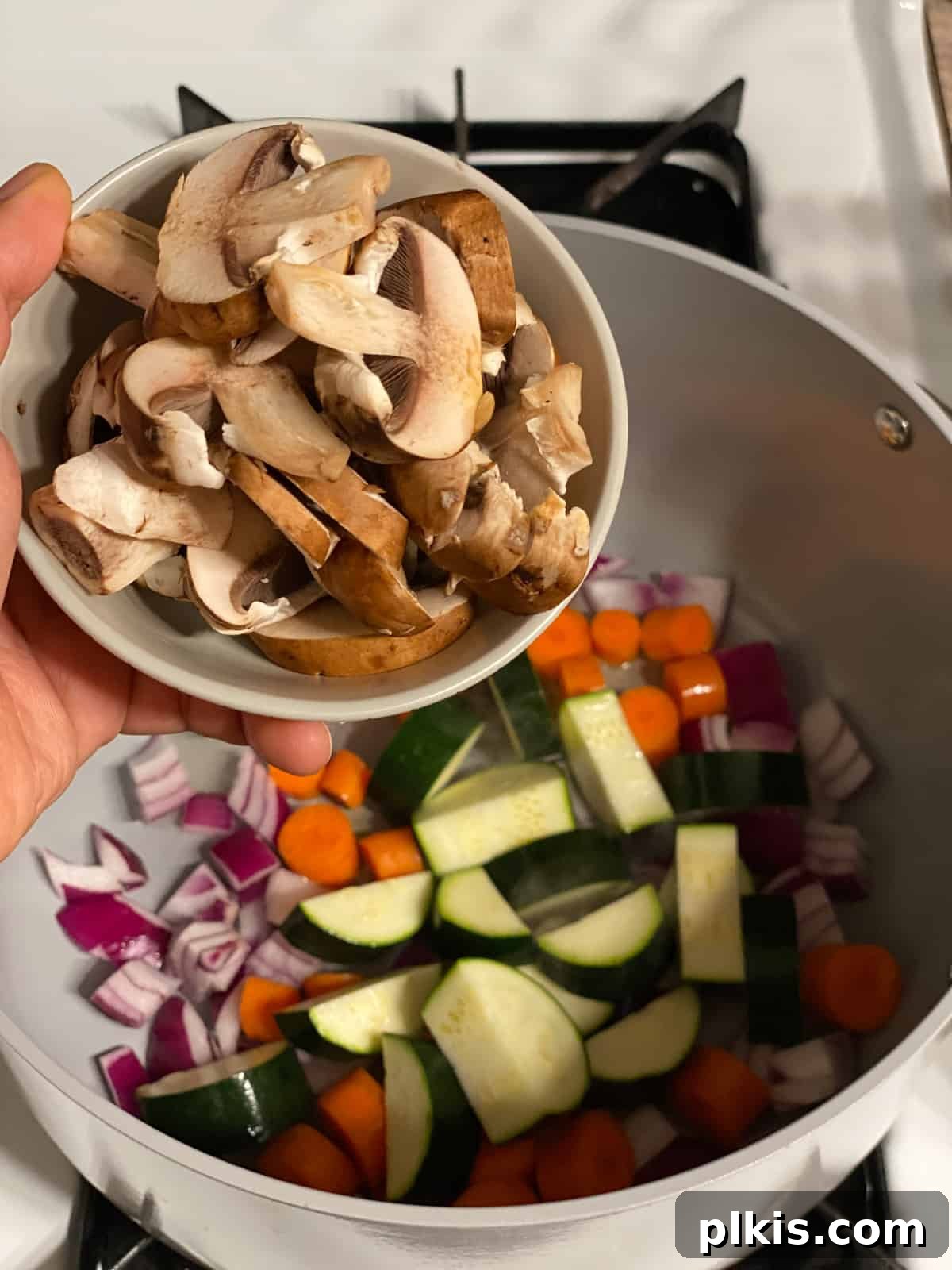 Hearty Tomato Potato Soup 7 Process shot of adding sliced mushrooms to the pan with other vegetables.