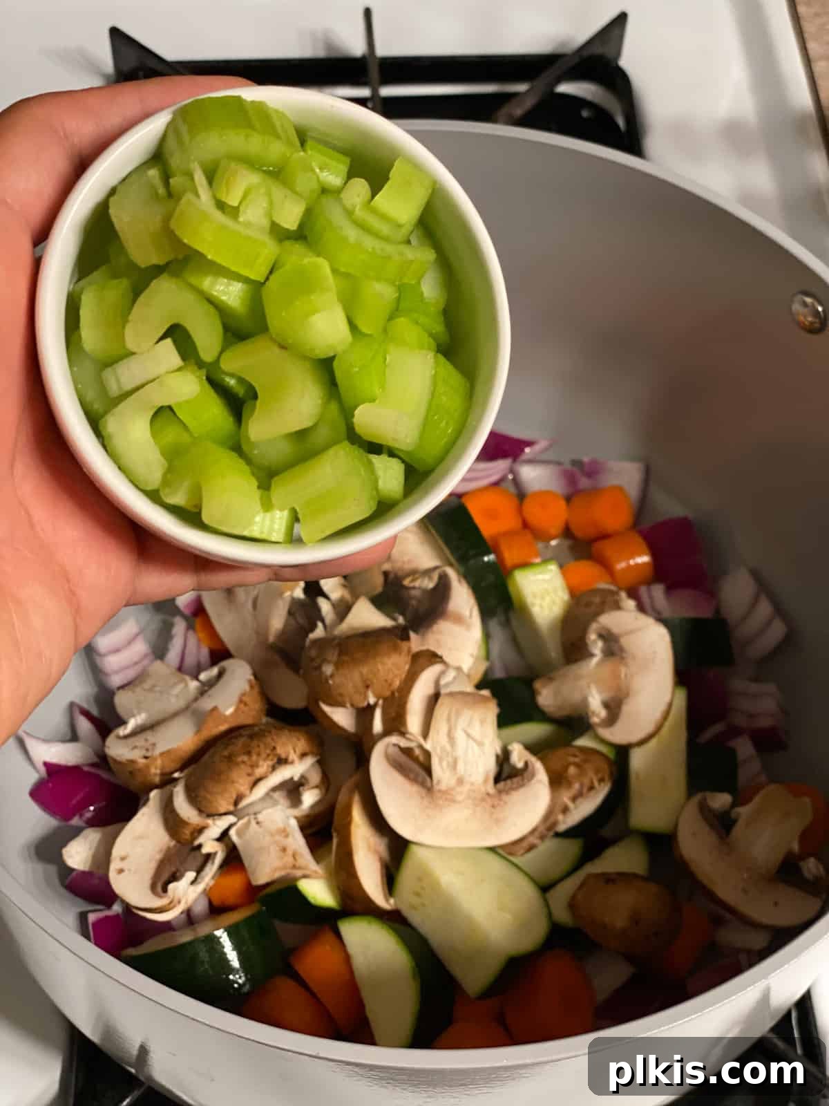 Hearty Tomato Potato Soup 8 Process shot of adding sliced celery to the pan with other vegetables.