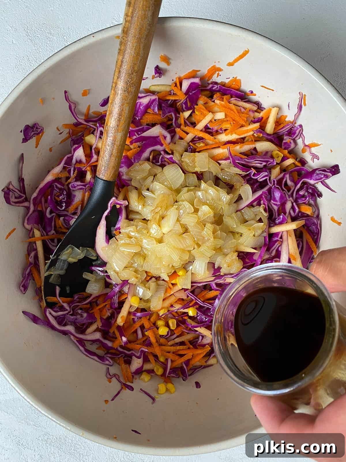 Garden Fresh Vegan Coleslaw with Apple, Carrots, and Corn 7 process of adding soy sauce and sugar mixture into bowl of veggies