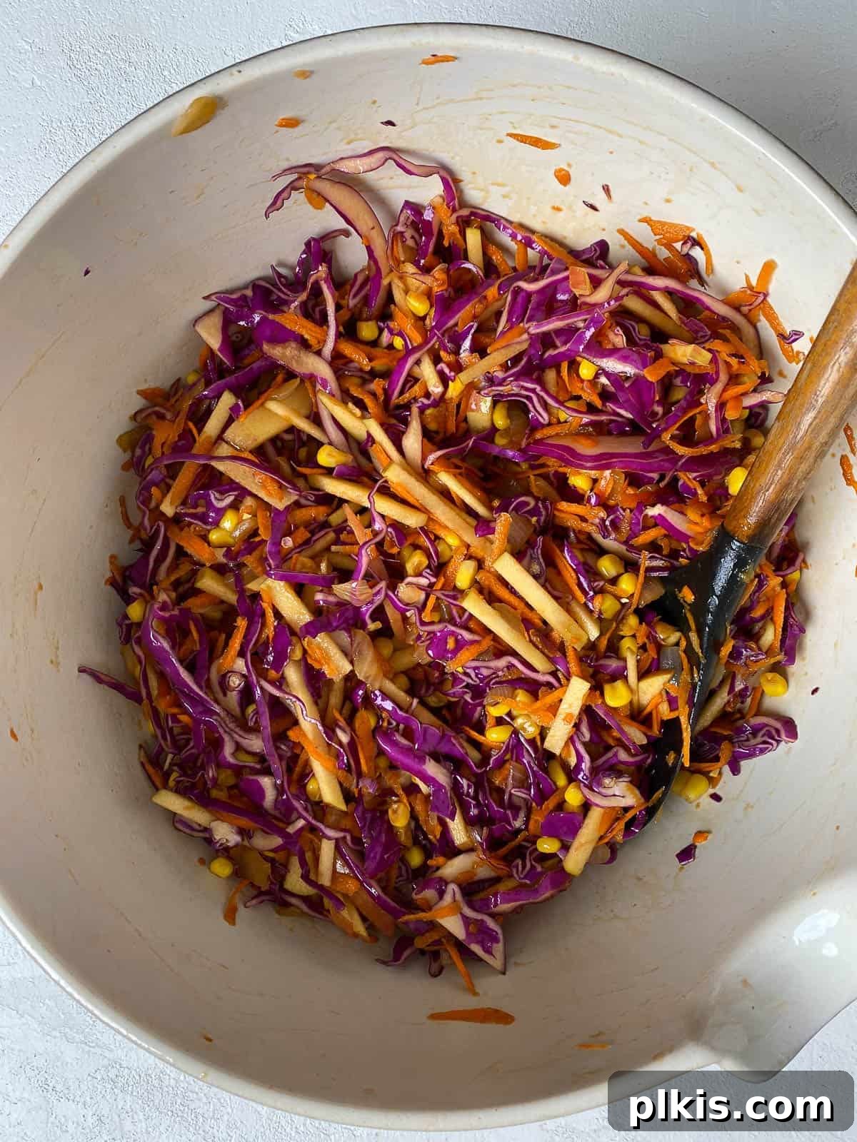 Garden Fresh Vegan Coleslaw with Apple, Carrots, and Corn 8 post mixing of sauce and veggies in white bowl