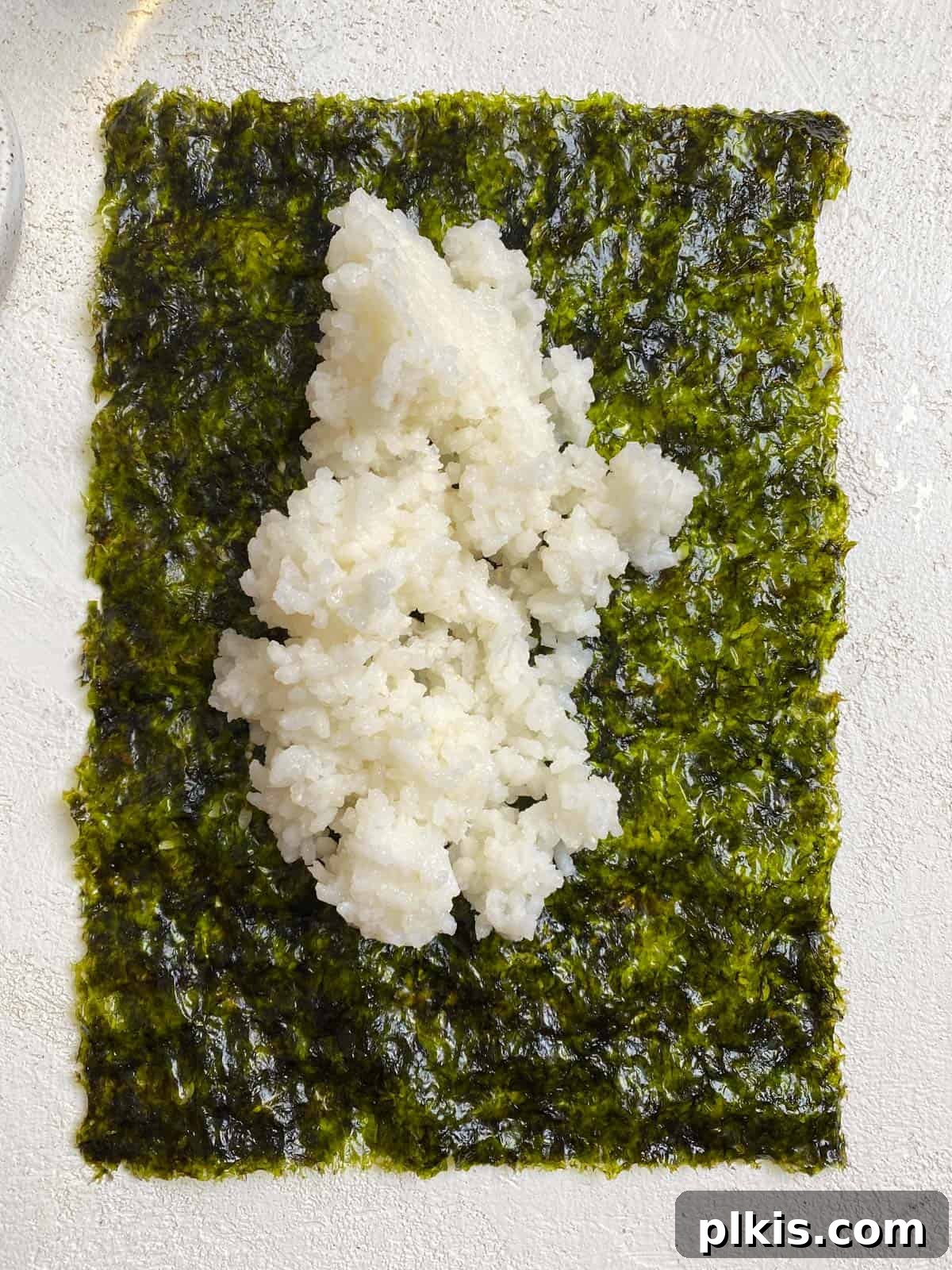 Plant-Powered Sushi Rolls 13 process shot of adding sushi rice to seaweed