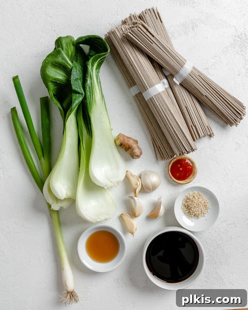 Savory Garlic Sesame Soba 3 Ingredients for Sesame Soba Noodles meticulously measured out in small white bowls, arranged on a clean white surface, showcasing the freshness and simplicity of the components.