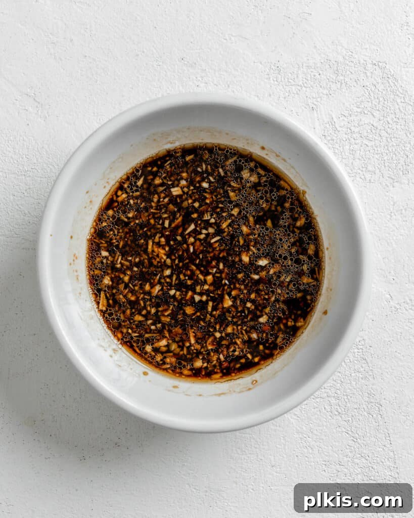 Savory Garlic Sesame Soba 4 Sesame Soba Noodle sauce, a rich blend of garlic, ginger, soy sauce, and sesame oil, in a small white bowl against a pristine white background, ready to be tossed with noodles and vegetables.