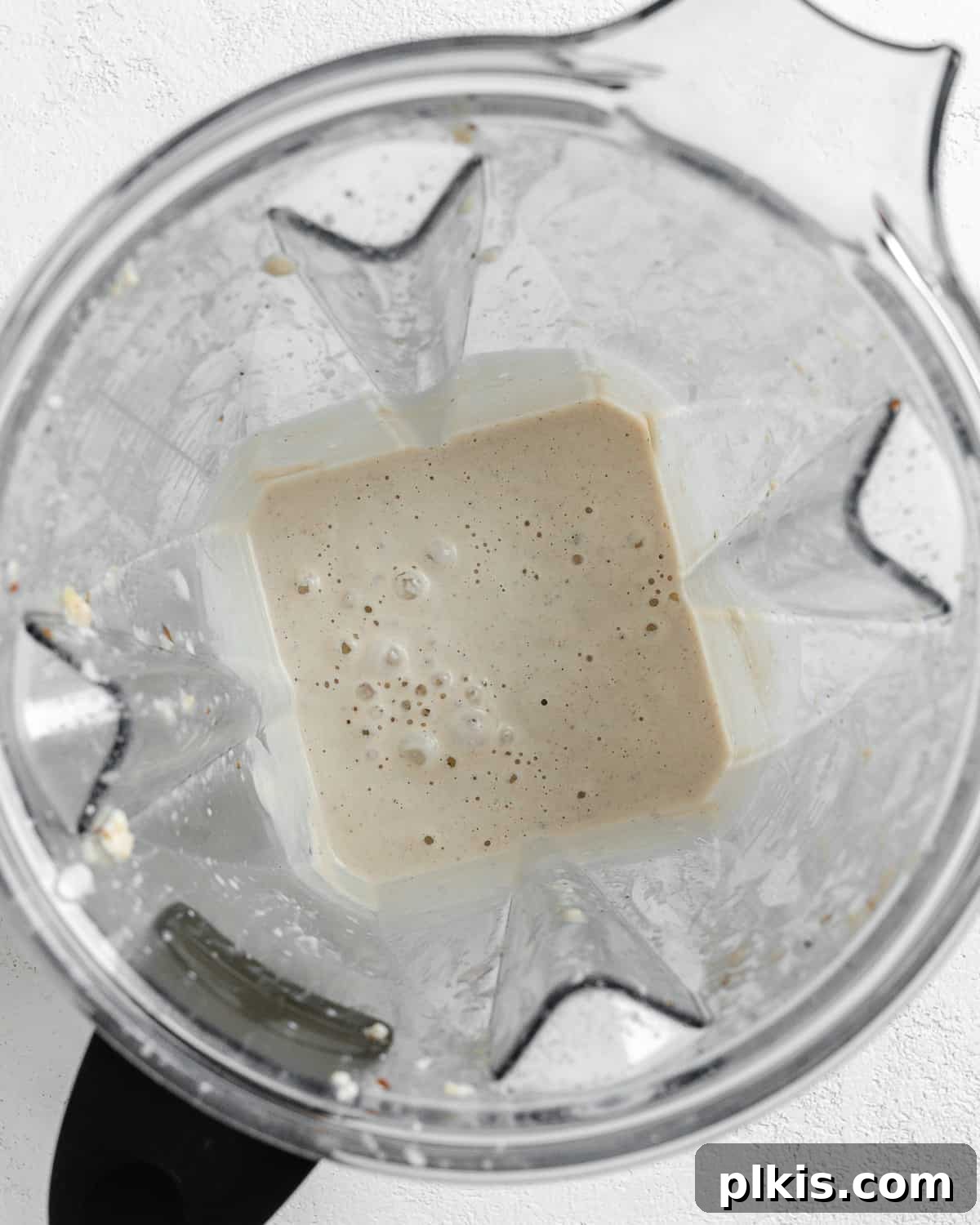 Process shot showing the post-blending stage of Creamy Vegan Garlic Sauce in a blender, illustrating a smooth and creamy texture.