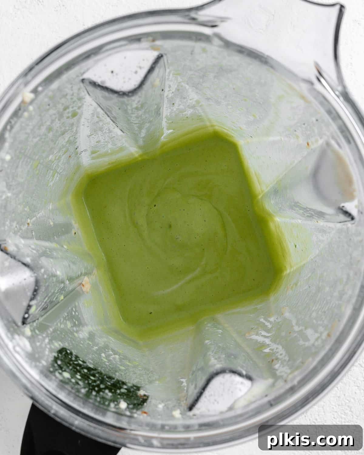 Process shot displaying the Creamy Vegan Garlic Sauce after blending in cilantro, showing a vibrant green hue and smooth texture.