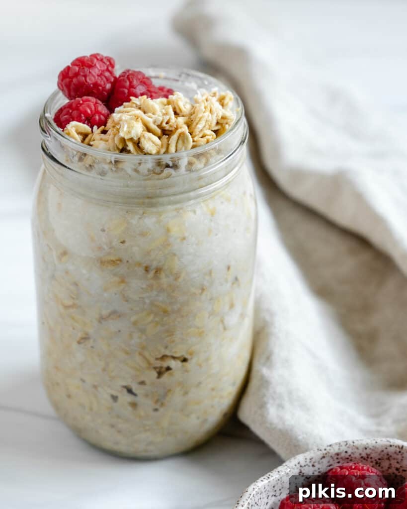 Tropical Coconut Overnight Oats 3 Two aesthetically pleasing jars of Coconut Overnight Oats on a bright background. One jar is open, showcasing a generous topping of fresh berries and golden granola, while the other is sealed, emphasizing the ease of storage and meal preparation for healthy breakfasts.