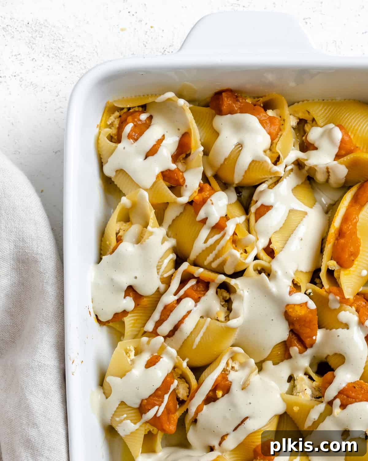 Autumn Pumpkin Pasta Shells with Aromatic Sage Cream 2 Delightful Pumpkin Stuffed Shells with Sage Cream in a white baking dish, ready to be served