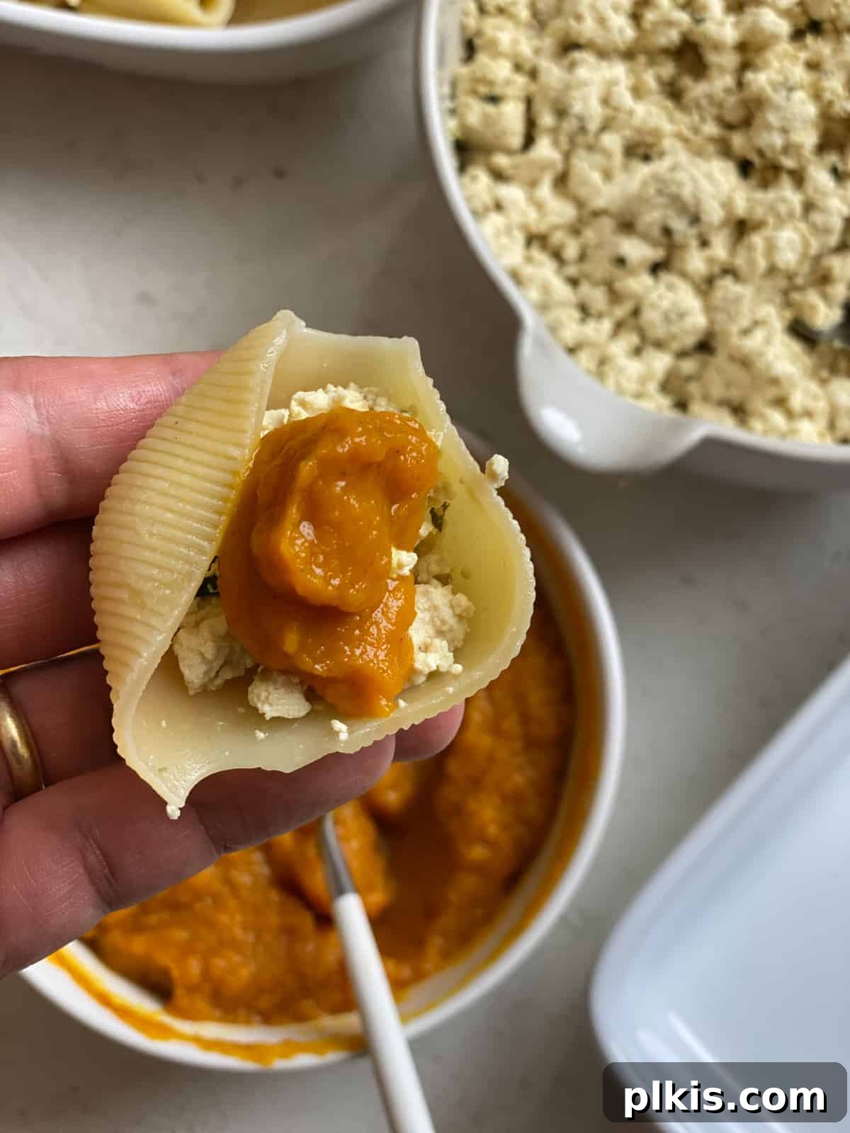Autumn Pumpkin Pasta Shells with Aromatic Sage Cream 12 Close-up of pumpkin filling being added on top of tofu ricotta in a stuffed shell