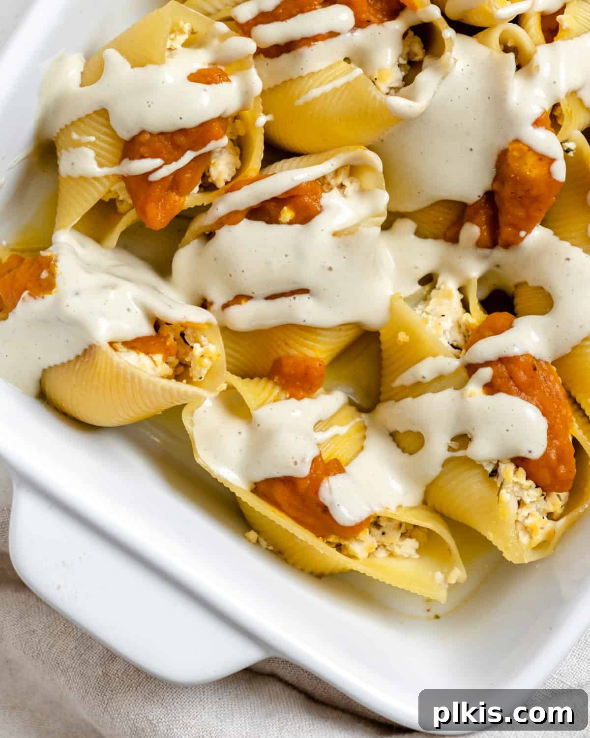 Autumn Pumpkin Pasta Shells with Aromatic Sage Cream 16 Finished Pumpkin Stuffed Shells with Sage Cream, glistening with sauce in a white baking dish