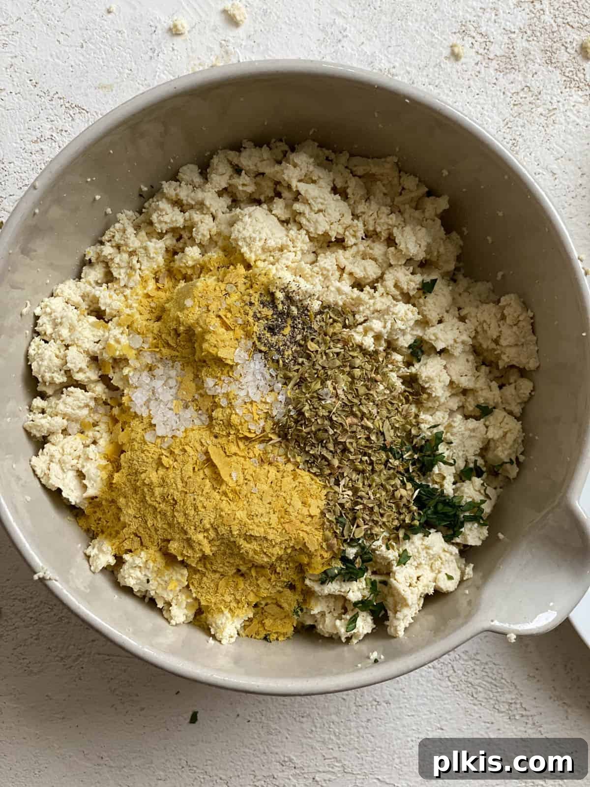 Autumn Pumpkin Pasta Shells with Aromatic Sage Cream 6 Seasonings being added to a bowl of crumbled tofu for the ricotta