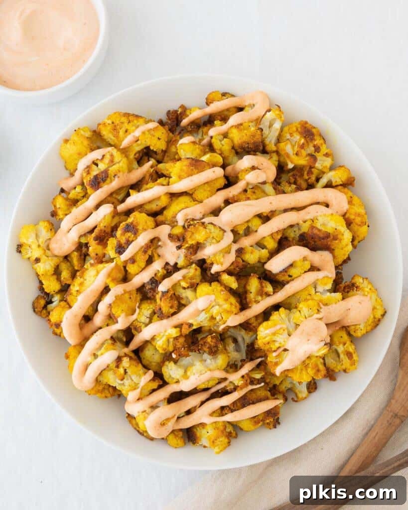 Effortless Crispy Cauliflower 2 Crispy, no-fuss cauliflower on a plate drizzled with tahini sauce, showcasing its golden-brown texture.