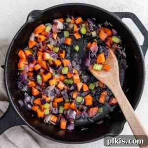 completed mirepoix in a black skilled with a wooden spoon