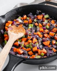 The Flavor Foundation 9 A close-up of fully cooked Mirepoix, with tender, translucent vegetables, in a black skillet, ready to flavor a variety of dishes.