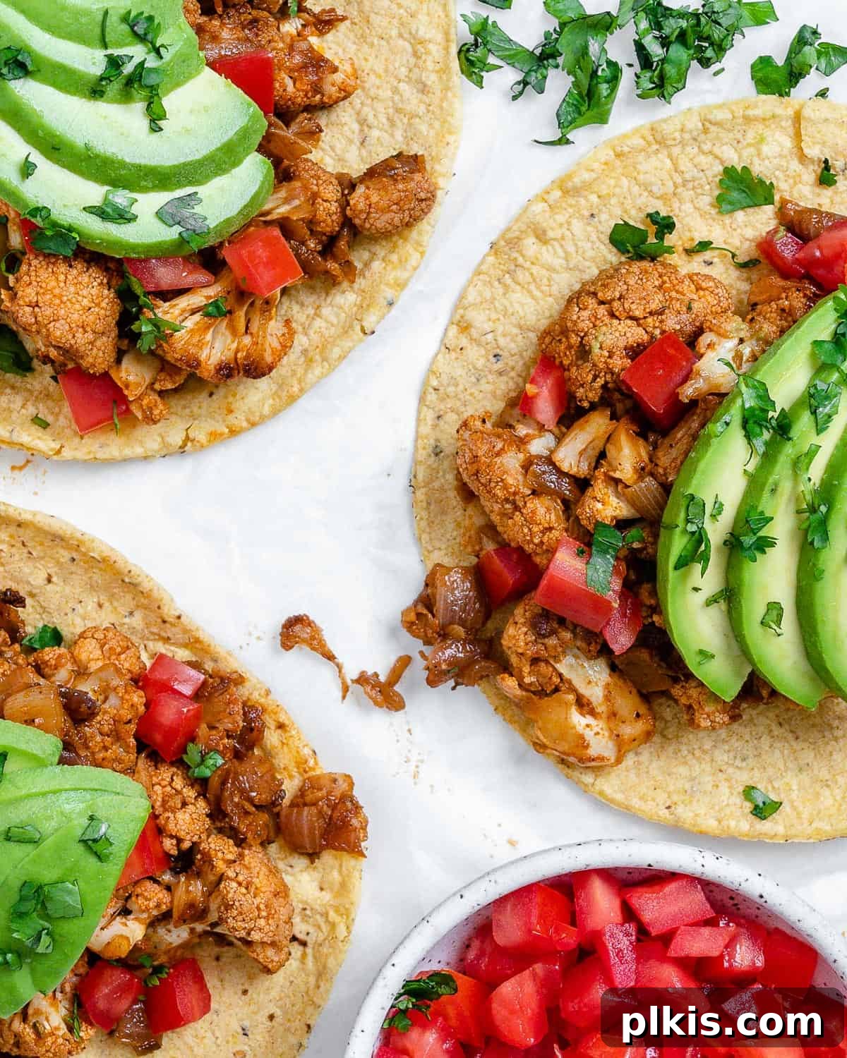 Roasted Cauliflower Tacos 13 An inviting close-up of a spread of Cauliflower and Lentil Tacos, showcasing their delicious filling and fresh toppings on a white backdrop.