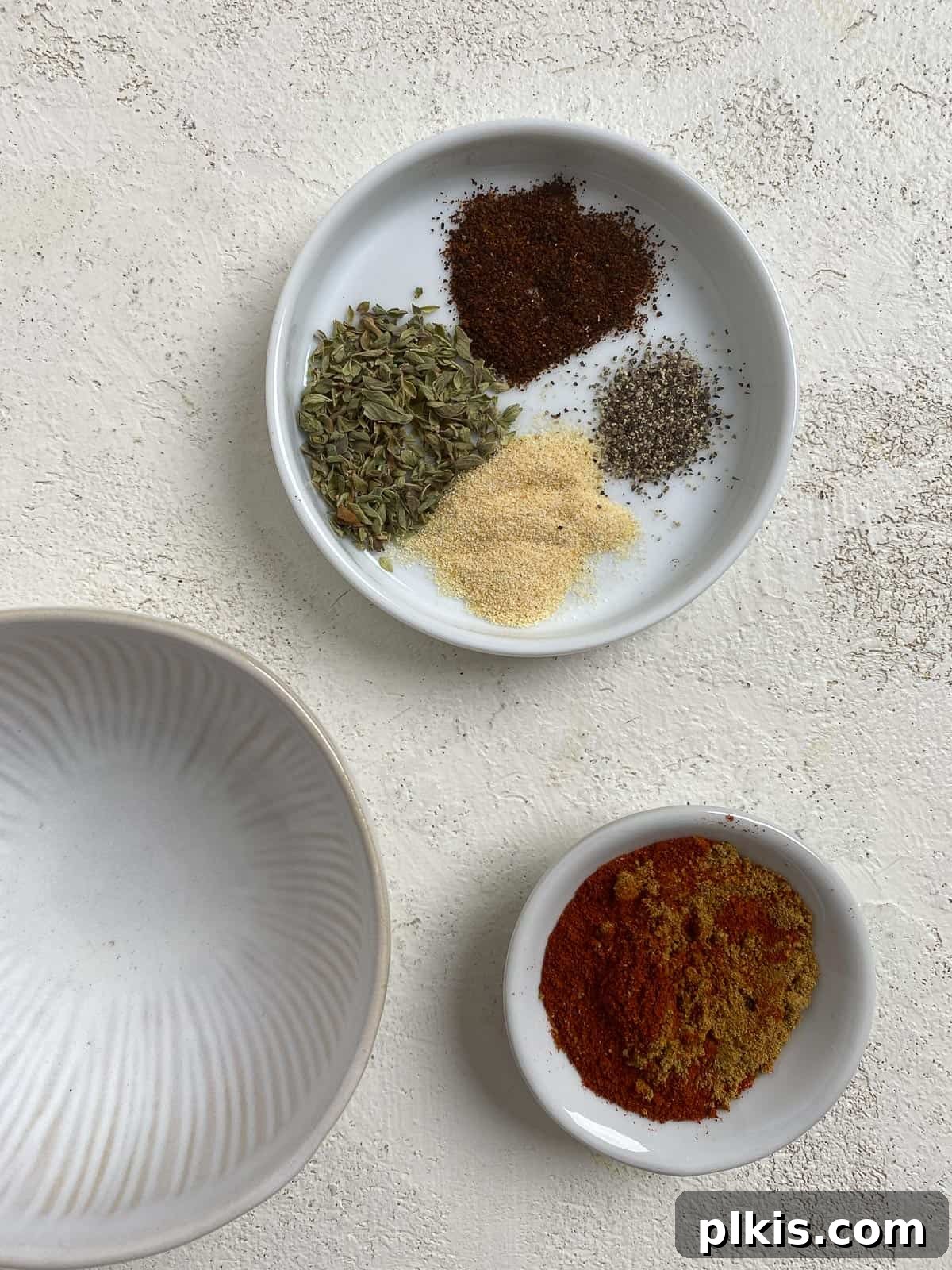 Roasted Cauliflower Tacos 5 Precisely measured taco spices, including cumin, paprika, oregano, garlic, and chili powder, arranged in small bowls on a light surface.