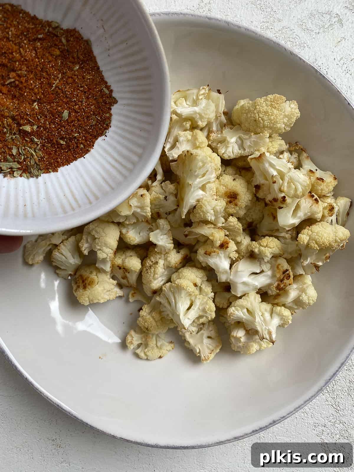 Roasted Cauliflower Tacos 8 Roasted cauliflower florets being coated with a generous amount of the taco spice blend in a bowl.