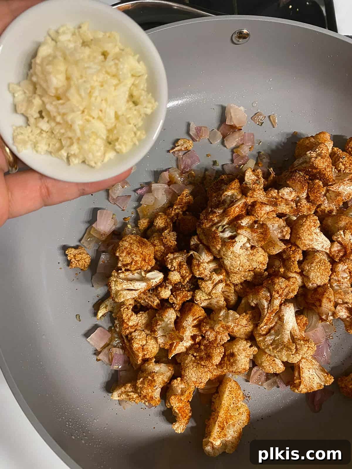 Roasted Cauliflower Tacos 10 Minced garlic being added to the pan with the cauliflower and onions, infusing the mixture with its pungent aroma.