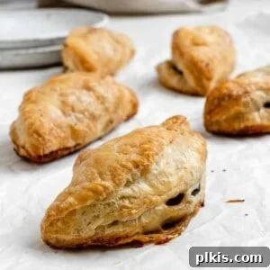 several completed Spinach and Mushroom Puffs [Vegan Hand Pies] scattered on a white surface