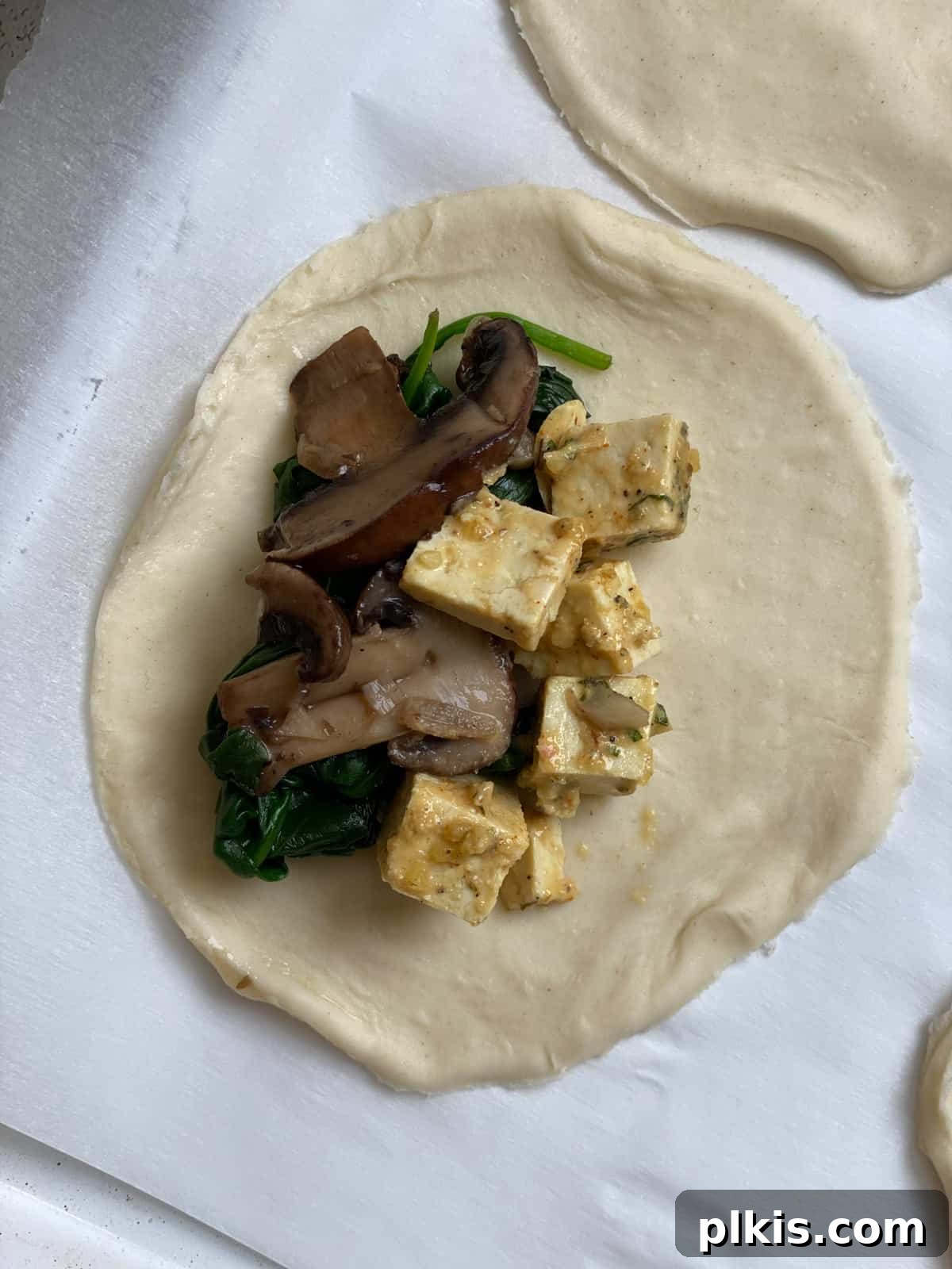 Savory Vegan Spinach Mushroom Pockets 8 Process shot of adding ingredients to dough.