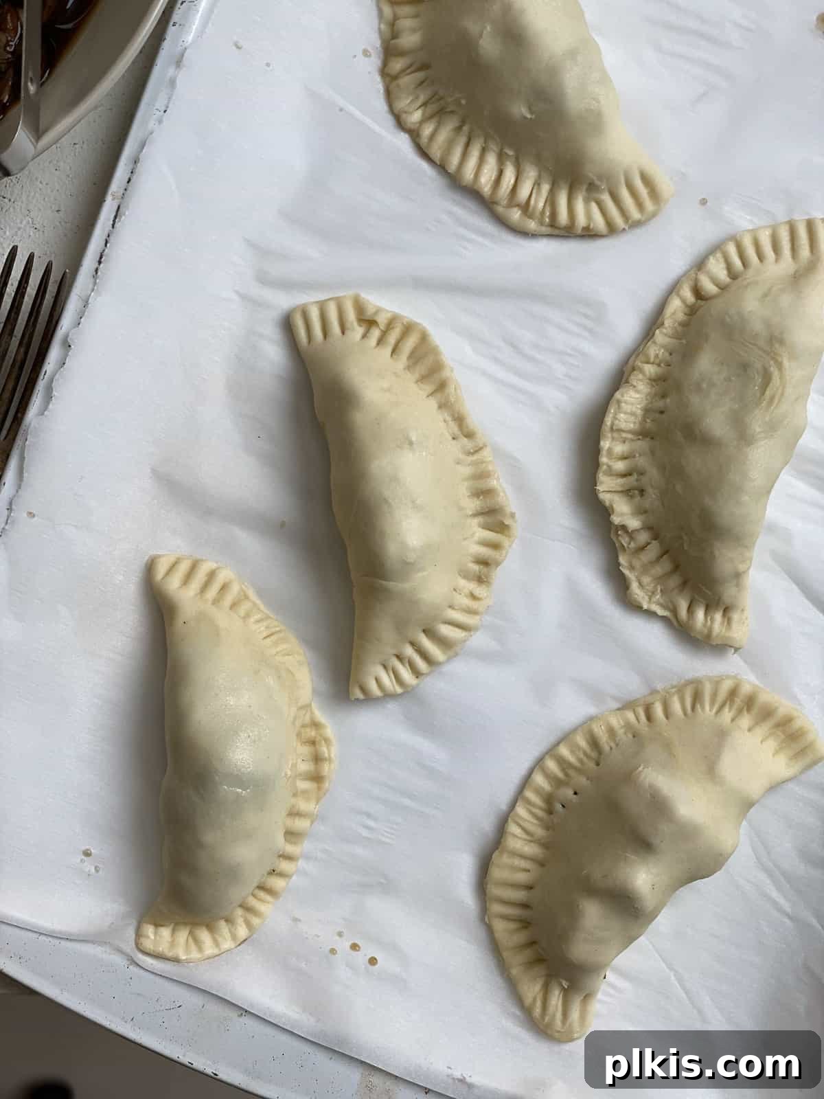 Several unbaked Spinach and Mushroom Puffs [Vegan Hand Pies] on a baking dish.