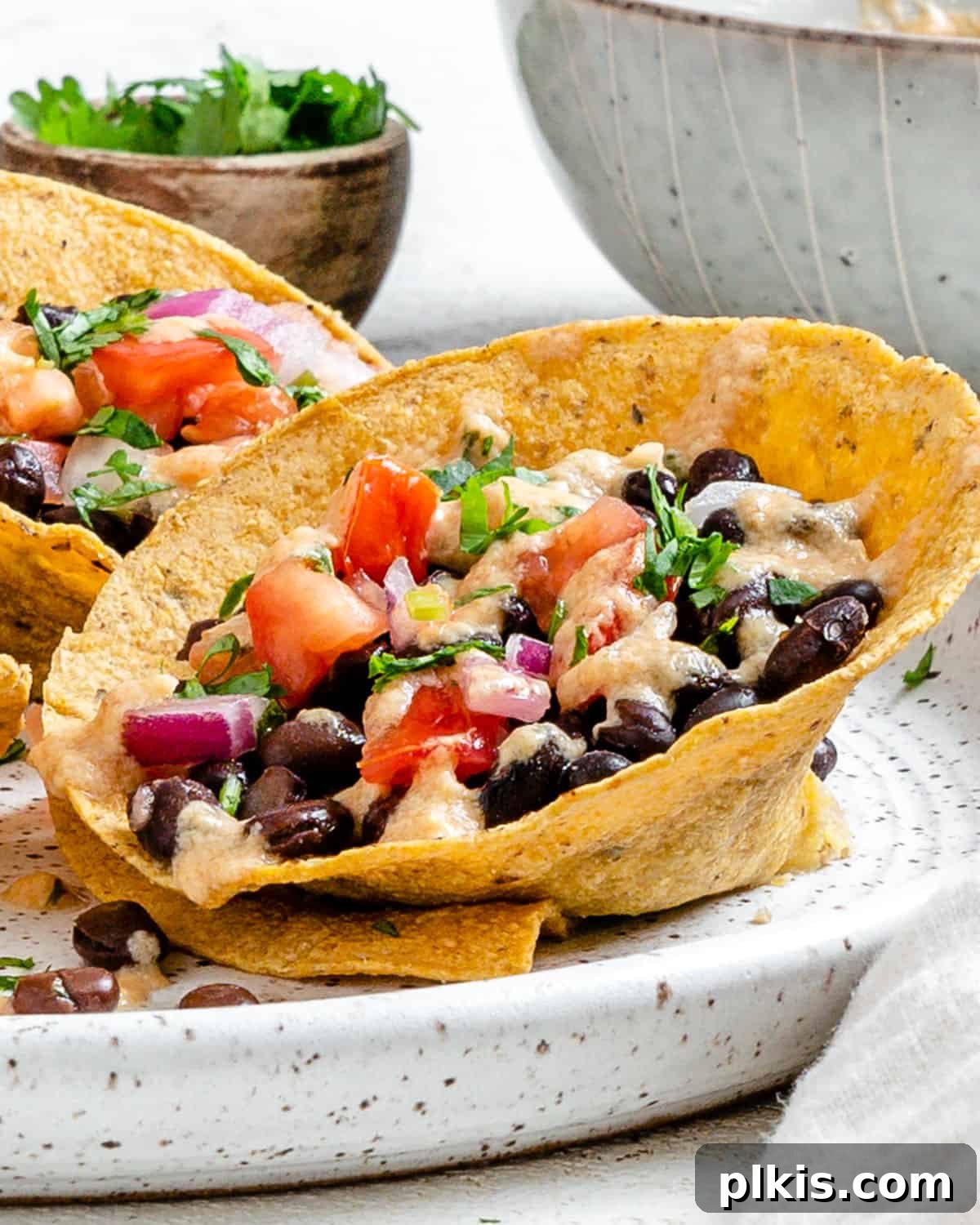 Zesty Black Bean Crunch Cups 2 completed Crunchy Taco Cups with Black Beans plated on a white speckled plate