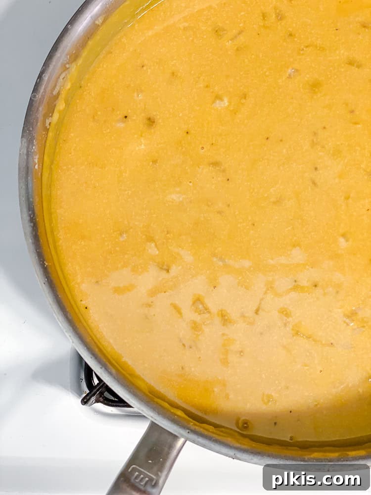 Ultimate Vegan Mac Bake 7 Process shot showing the vegan cheese sauce simmering and thickening in a saucepan.