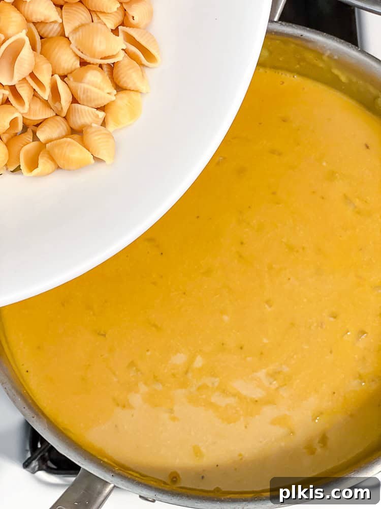 Ultimate Vegan Mac Bake 8 Process shot showing cooked pasta being stirred into the creamy vegan cheese sauce.