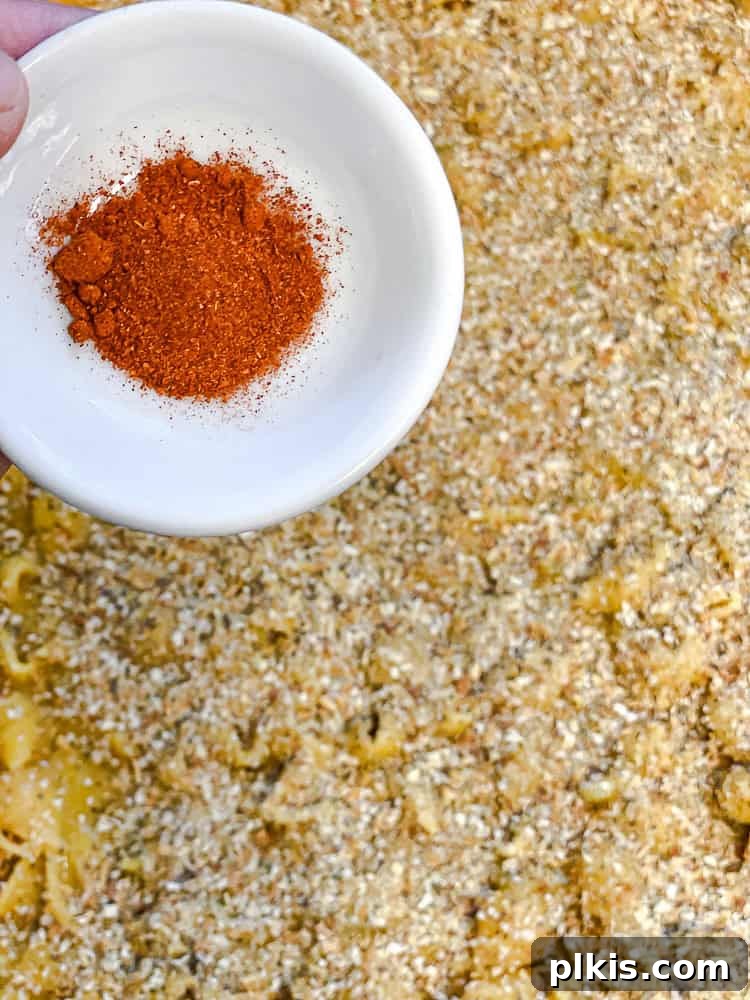 Ultimate Vegan Mac Bake 9 Process shot showing the vegan mac and cheese in a casserole dish topped with breadcrumbs and paprika, ready for baking.