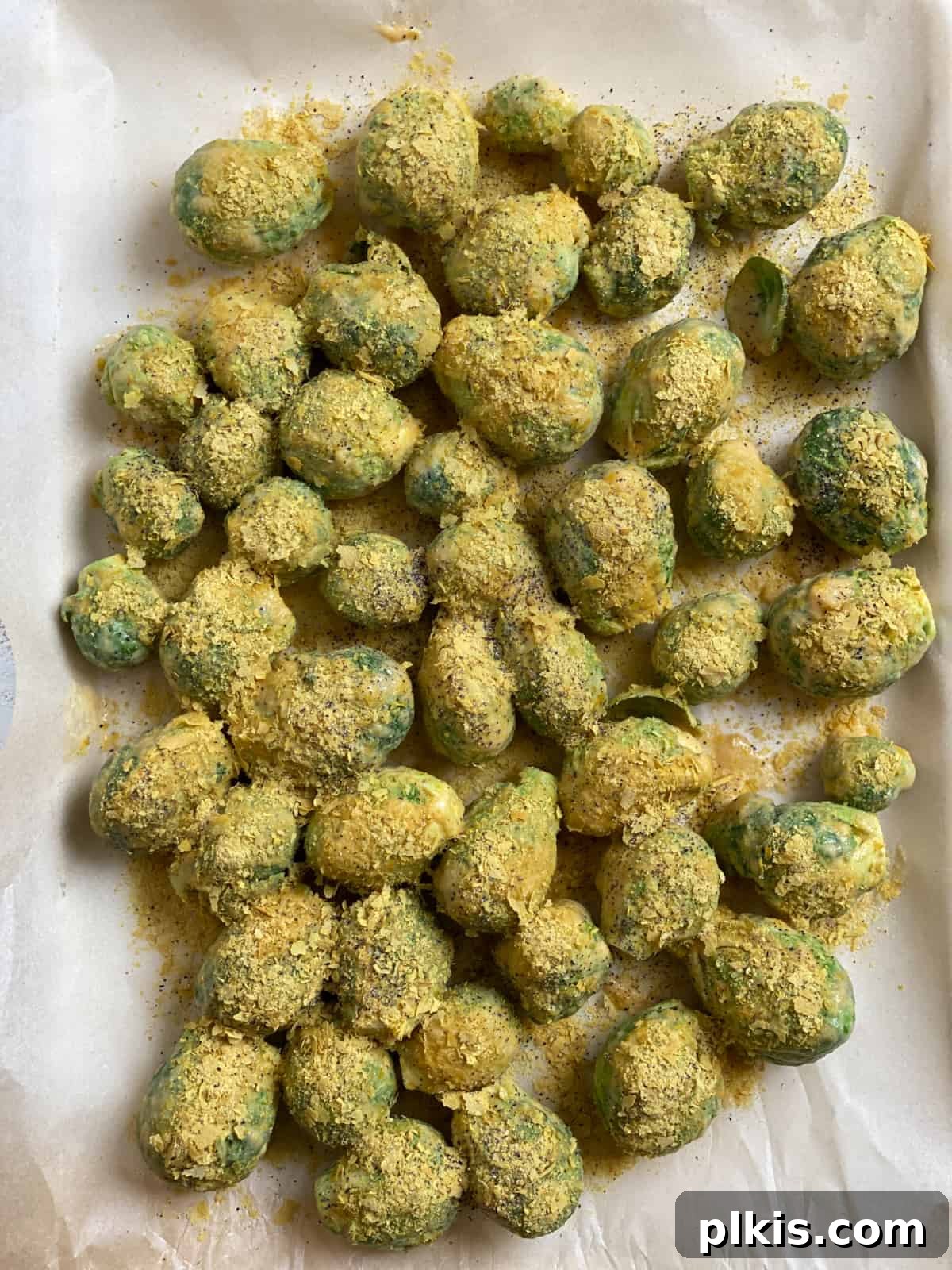 Effortless Vegan Brussels Sprouts Delight 12 Seasoned Brussels sprouts on a baking sheet, ready to be placed in the oven