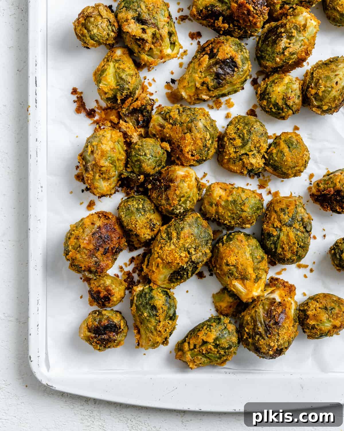 Effortless Vegan Brussels Sprouts Delight 13 A generous serving of Easy Vegan Brussels Sprouts with Tahini, perfectly roasted and scattered on a white surface, garnished with fresh herbs
