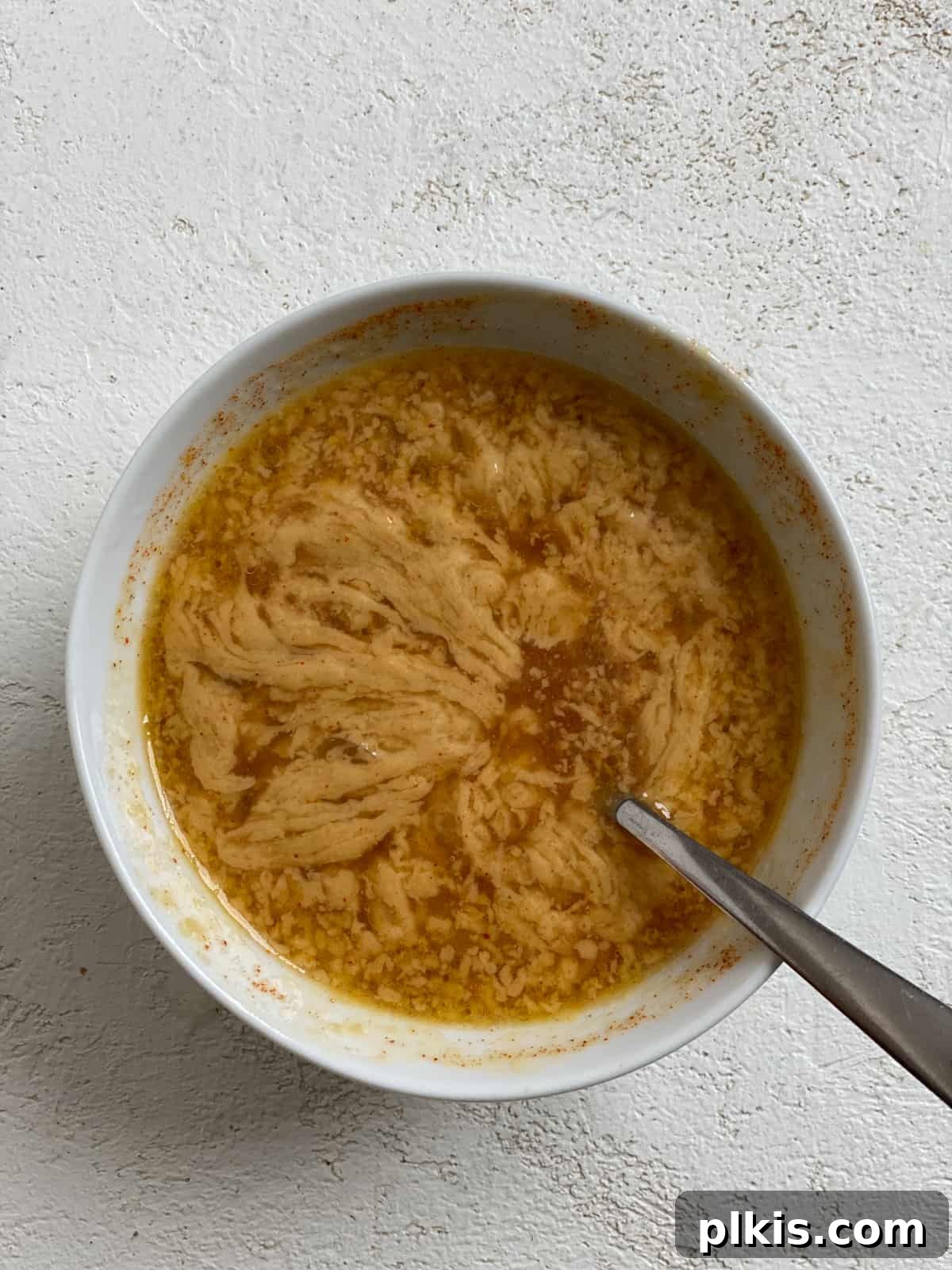 Effortless Vegan Brussels Sprouts Delight 5 Mixing tahini, water, oil, and spices in a small white bowl to create a smooth sauce