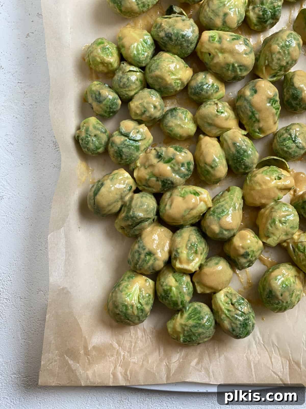 Effortless Vegan Brussels Sprouts Delight 9 Coated Brussels sprouts spread evenly on a baking sheet, ready for the oven