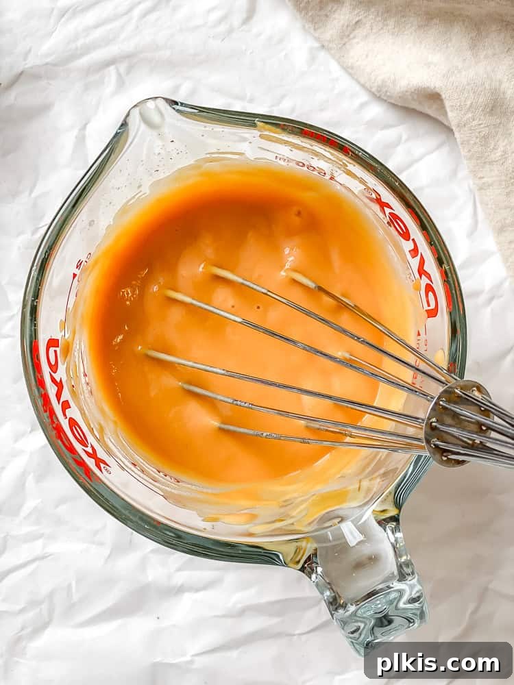Velvet Sweet Potato Biscuits 4 Process shot showing whisking sweet potato puree and plant milk together in a measuring cup.
