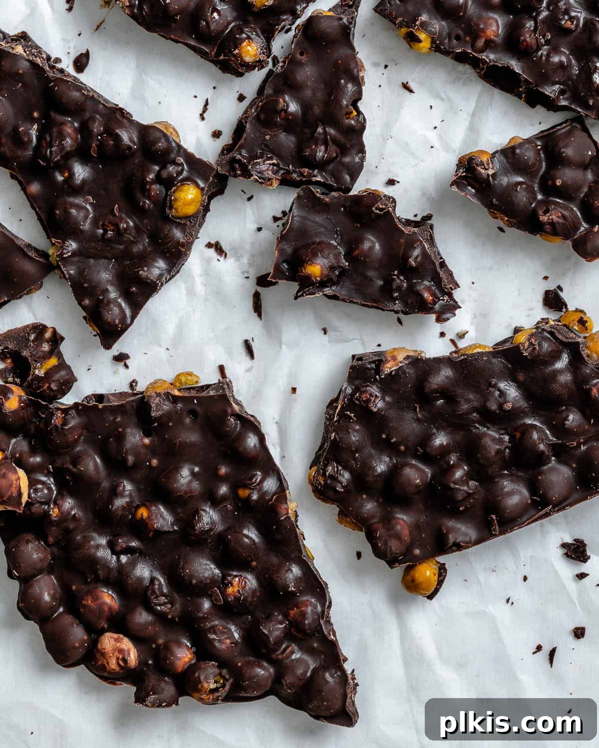 Irresistible Chocolate Chickpea Bites 2 Delicious chocolate covered chickpeas bark sprinkled with flaky salt on a white surface, ready to be enjoyed as a healthy snack.