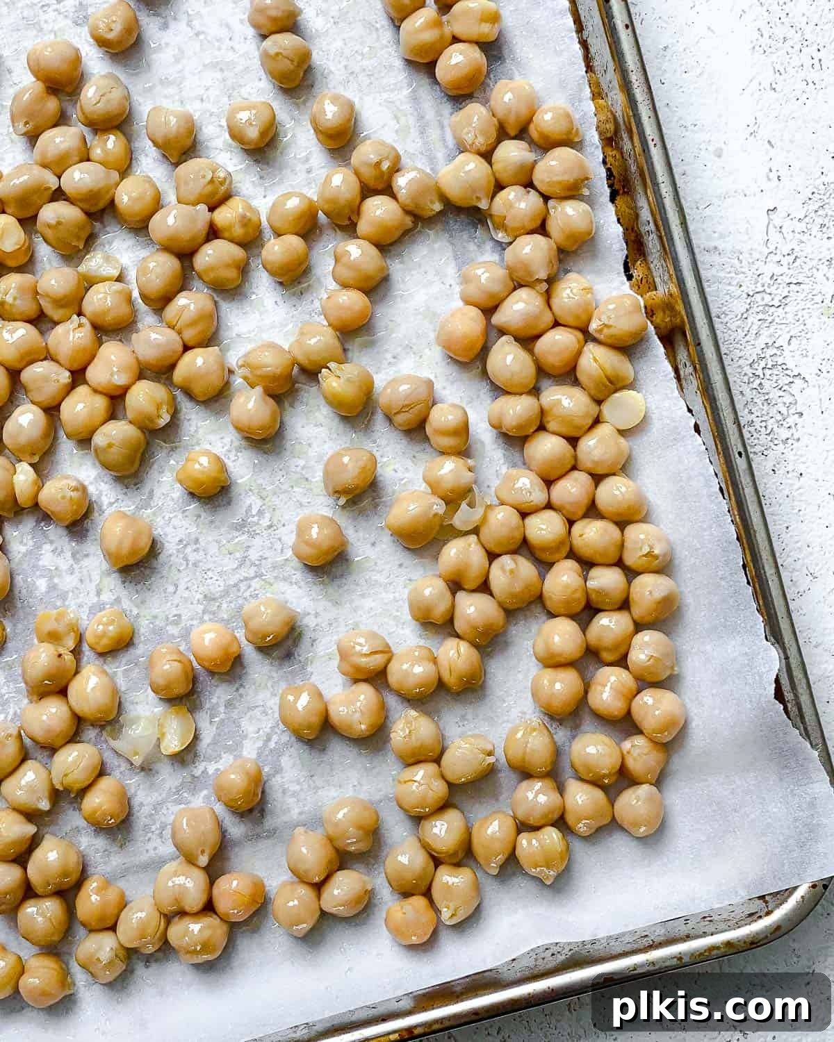 Irresistible Chocolate Chickpea Bites 5 Chickpeas evenly spread on a parchment-lined baking tray, ready for roasting.