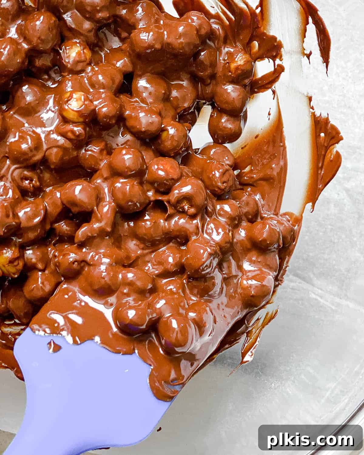 Irresistible Chocolate Chickpea Bites 7 Crispy chickpeas being tossed with melted vegan chocolate in a bowl, ensuring an even coating.