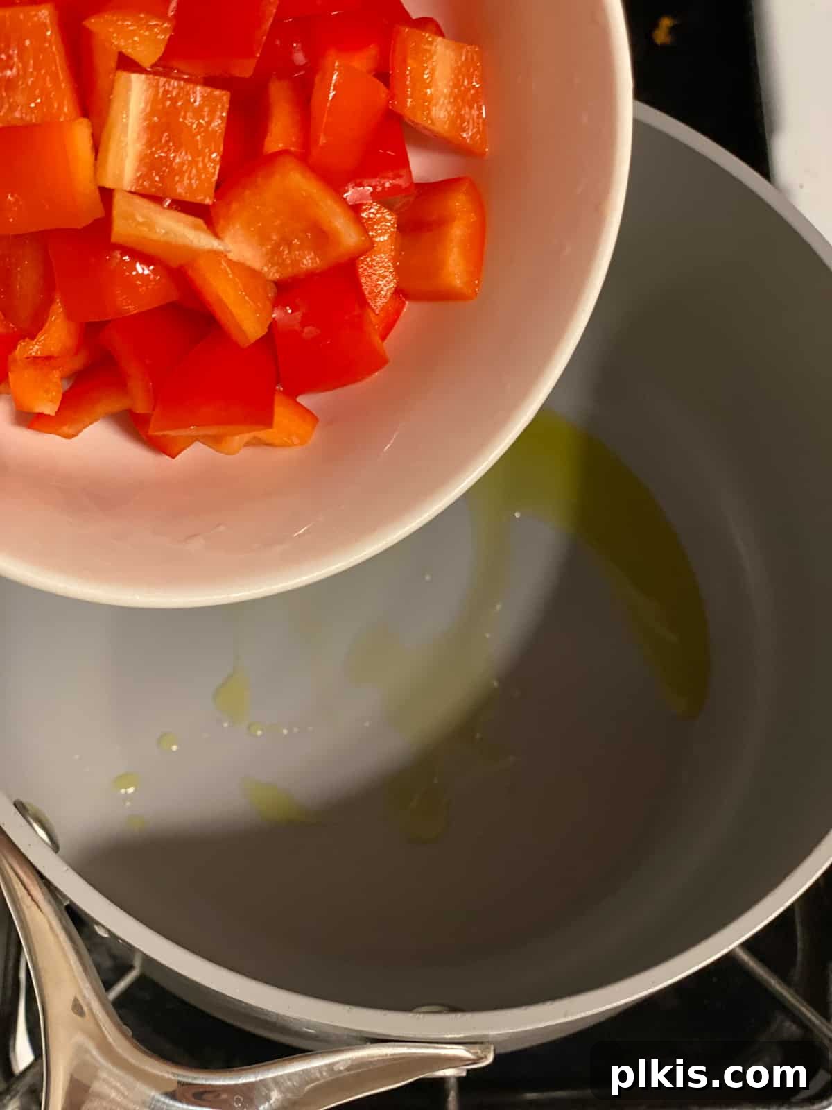 Pantry-Friendly Vegan Tomato Soup 4 Process shot of adding diced red bell pepper to a pan with hot oil.