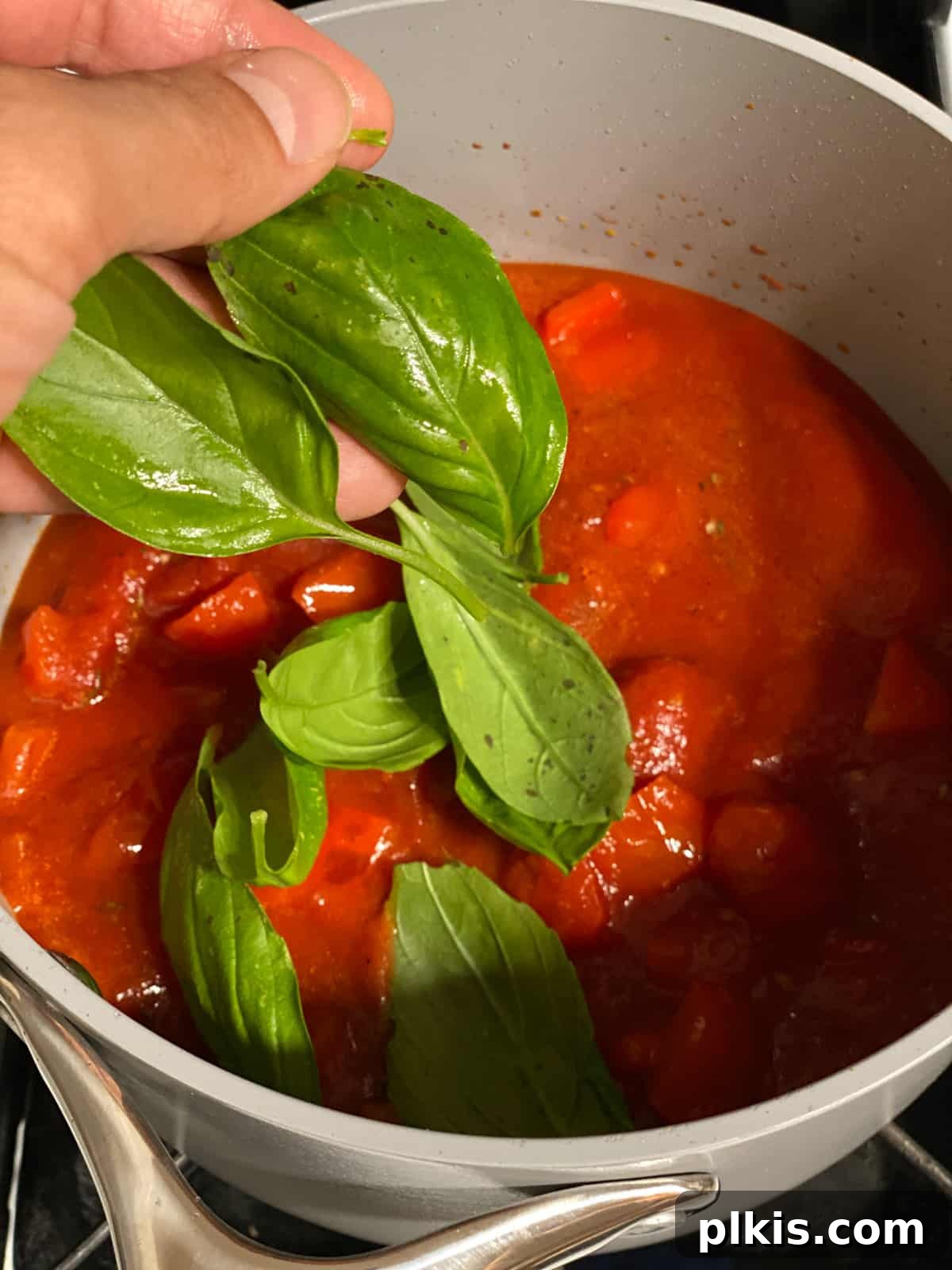 Pantry-Friendly Vegan Tomato Soup 8 Process shot of adding fresh basil leaves to the simmering tomato soup base.
