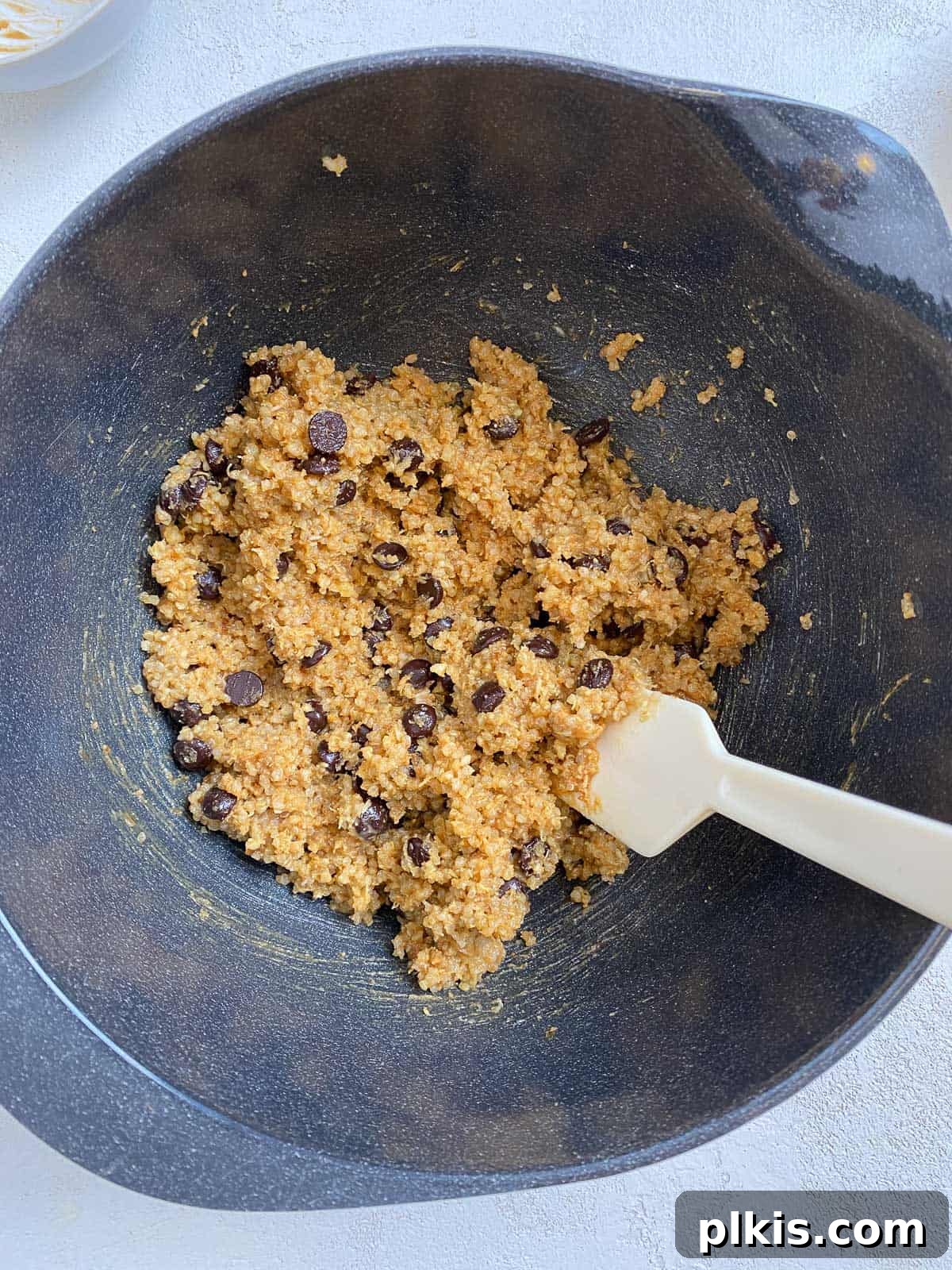 Plant-Powered Quinoa Chocolate Chip Cookies 4 A close-up shot of ingredients for Vegan Chocolate Chip Quinoa Cookies being mixed together in a large bowl, showing a harmonious blend of textures.