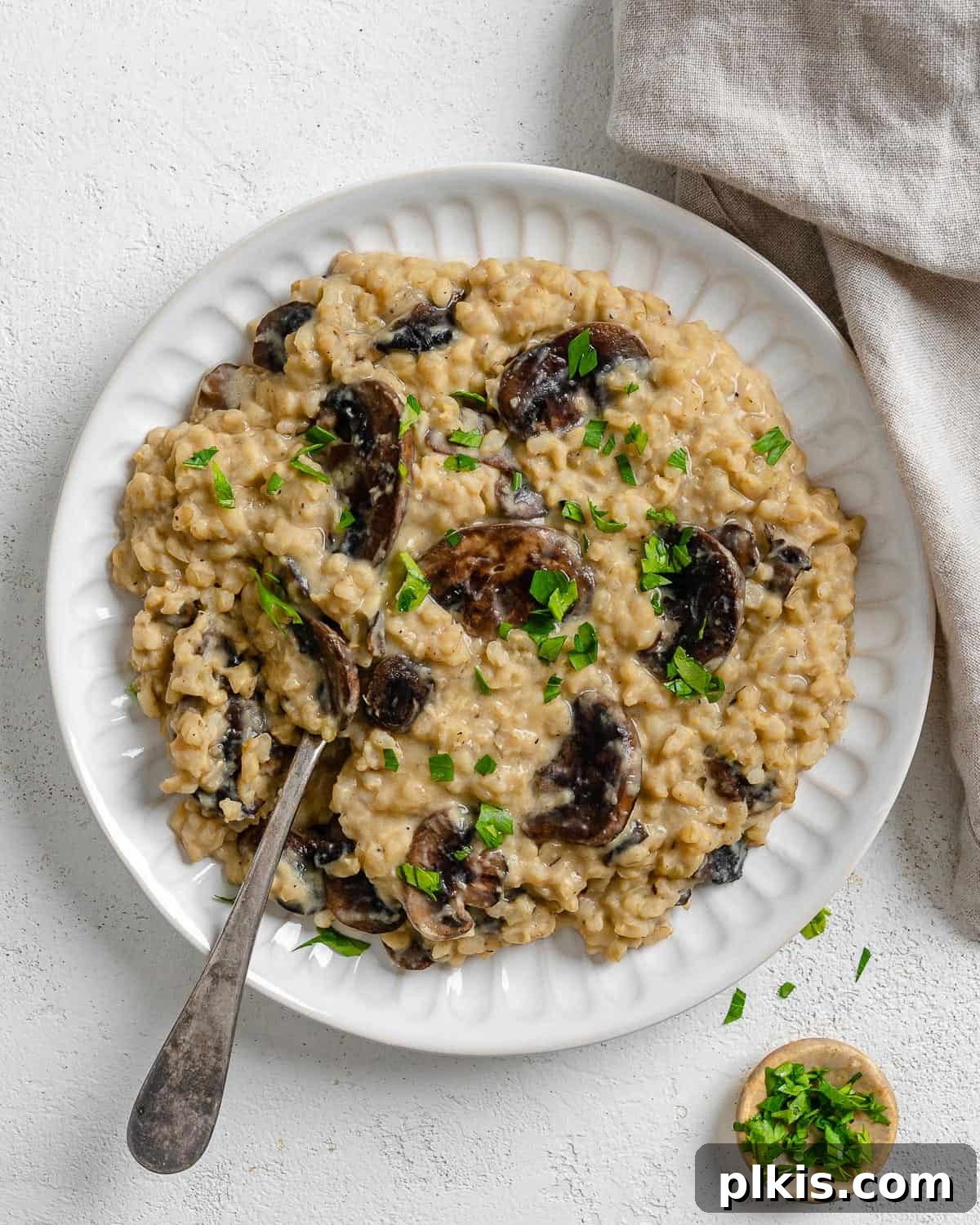 Velvety Brown Rice Risotto 2 Completed Creamy Brown Rice Risotto plated beautifully against a light surface, garnished with fresh herbs.