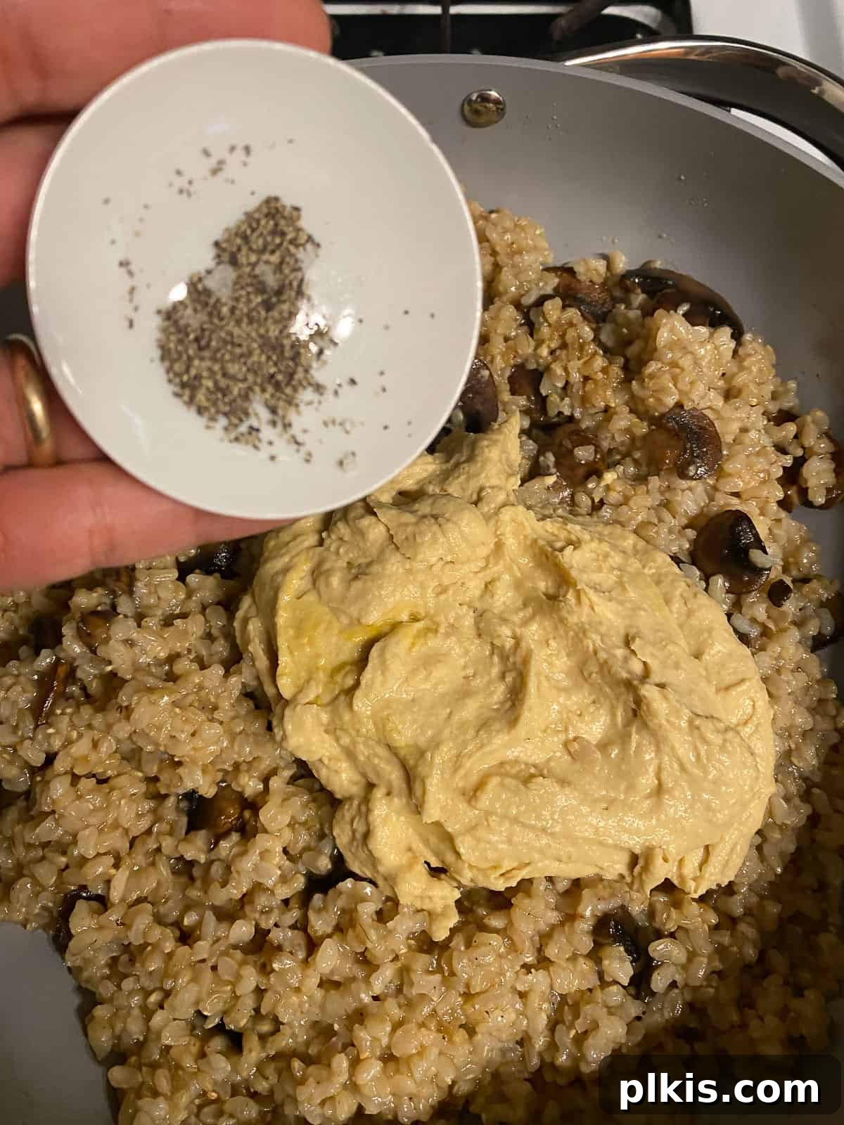 Velvety Brown Rice Risotto 11 Process shot of adding seasonings, like garlic powder, salt, and pepper, to the risotto.