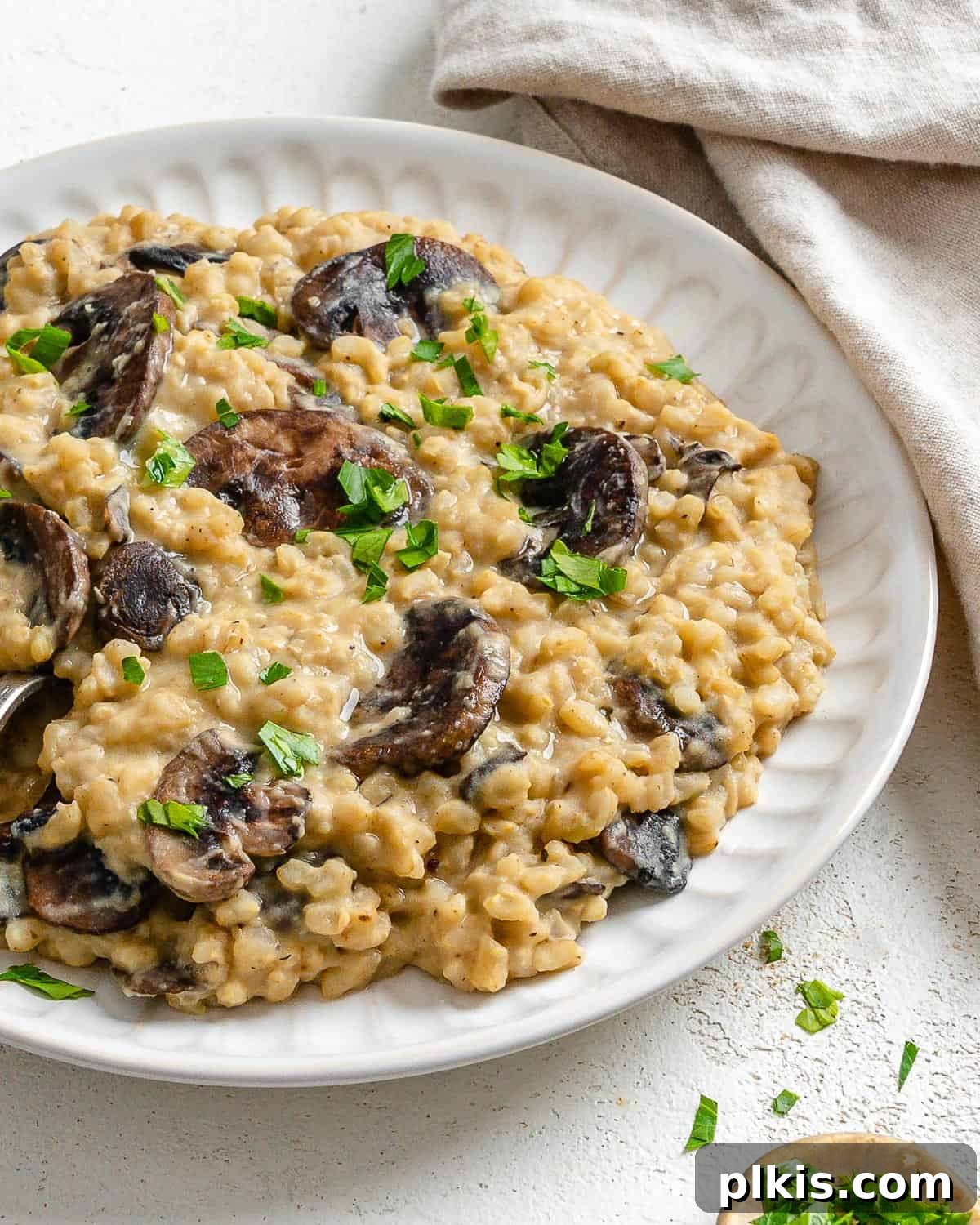 Velvety Brown Rice Risotto 13 Completed Creamy Brown Rice Risotto plated against a light surface, garnished with fresh herbs, ready to be served.